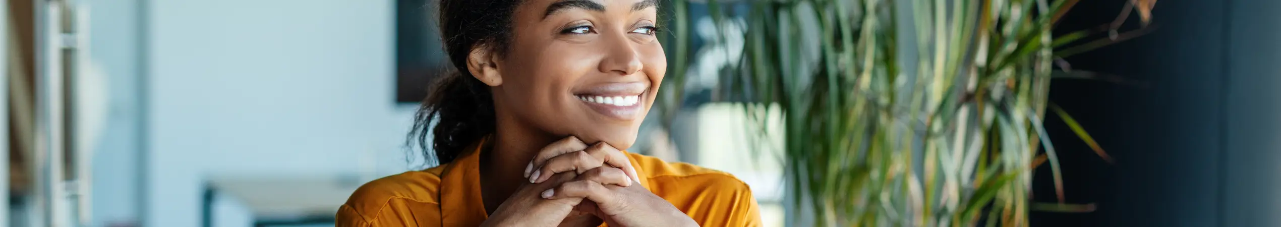 Portrait of dreamy african american businesswoman sitting at desk in office and thinking while working on laptop